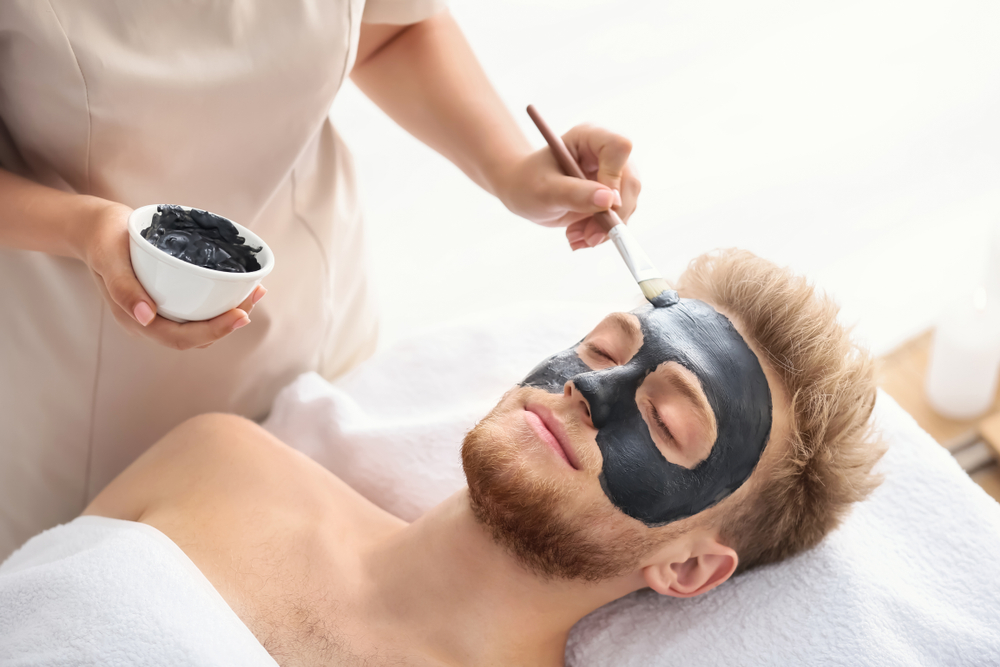 Cosmetologist,Applying,Mask,On,Man's,Face,In,Spa,Salon